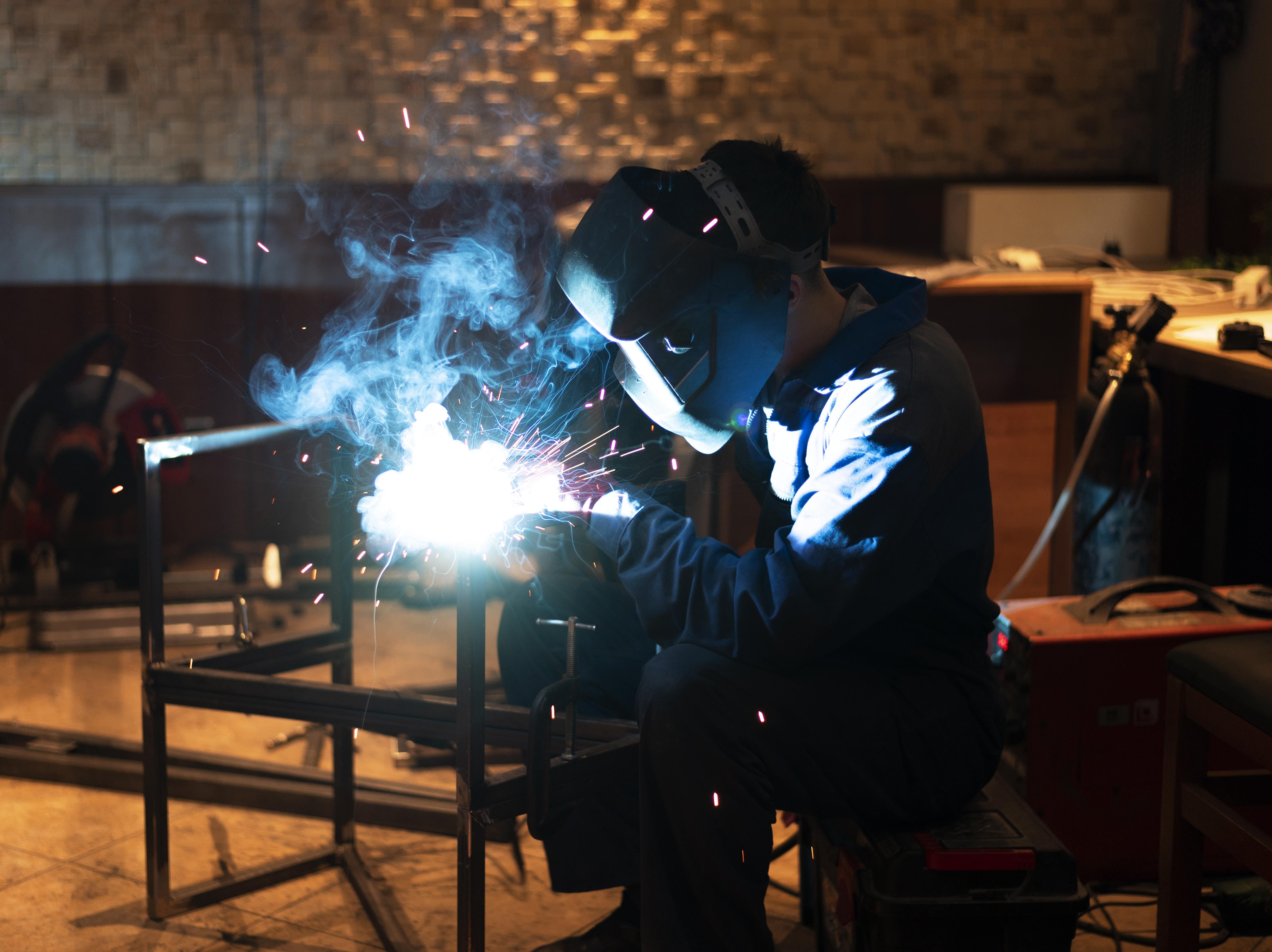 Man with mask welding metal at atelier